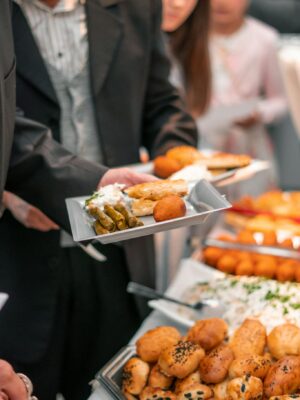 A business event with adults enjoying a diverse buffet featuring bread, pastries, and salads.