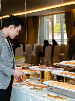 Man selecting pastries from a buffet at a corporate event indoors.